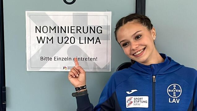 Eine Sportlerin zeigt auf ein Schild