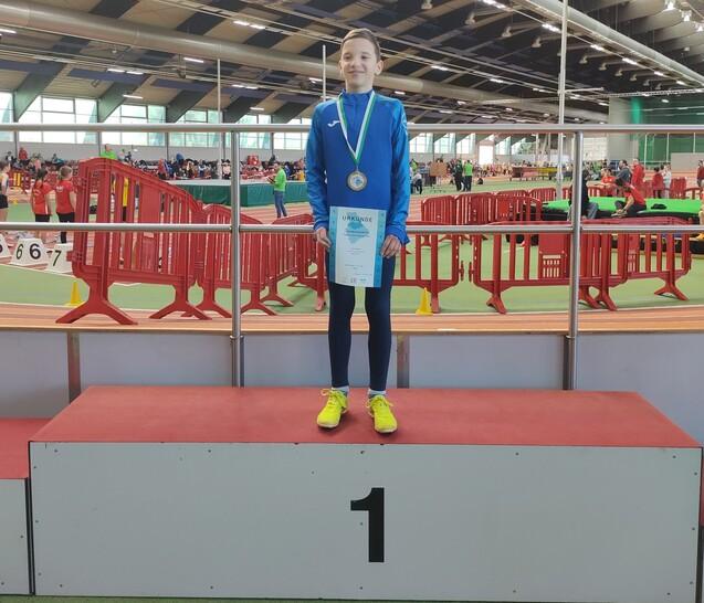 Junge mit Medaille und Urkunde auf dem Siegerpodest
