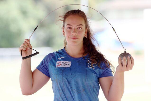 Sportlerin zeigt ihr Sportgerät, einen Hammer