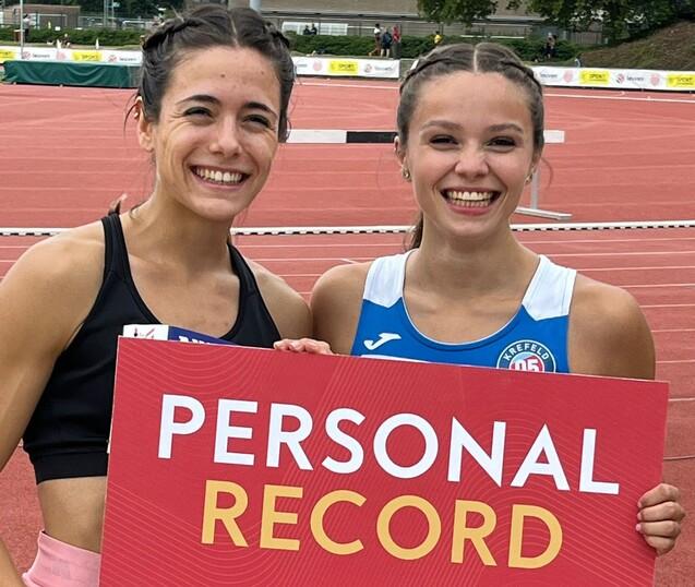 Zwei Sportlerinnen zeigen ein Schild f&uuml;r die pers&ouml;nliche Bestzeit