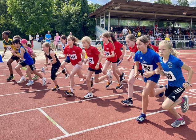 Zahlreiche Kinder laufen nebeneinander auf der Tartanbahn