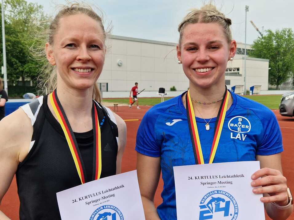 Zwei Sportlerinnen mit Medaillen und Urkunden