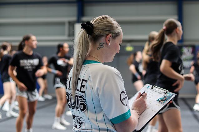Eine Trainerin macht sich beim Cheerleading Notizen