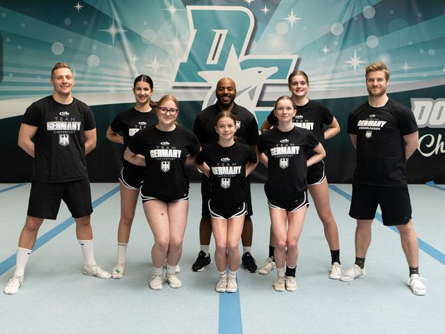Acht Cheerleader*innen im Outfit des Nationalteams
