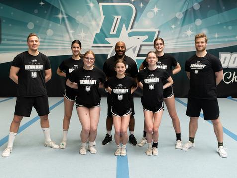 Acht Cheerleader*innen im Outfit des Nationalteams