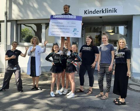 Cheerleaderinnen &uuml;bergeben einen Spendenscheck