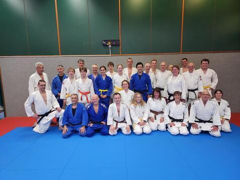 Eine Gruppe Judoka sitzt auf einer blauen Judomatte