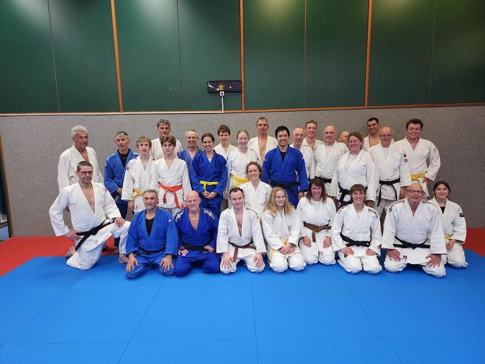 Eine Gruppe Judoka sitzt auf einer blauen Judomatte