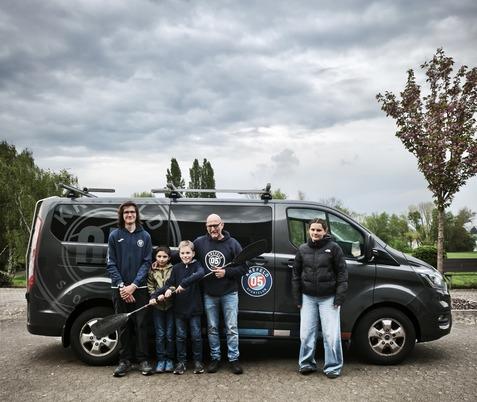 Zwei Kinder und drei Erwachsene stehen vor einem Sprinter