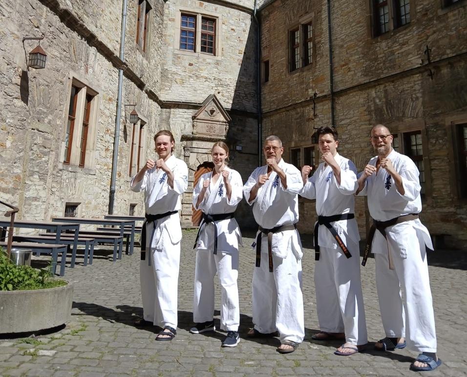 F&uuml;nf Menschen in wei&szlig;en Karate-Anz&uuml;gen vor einer Burg