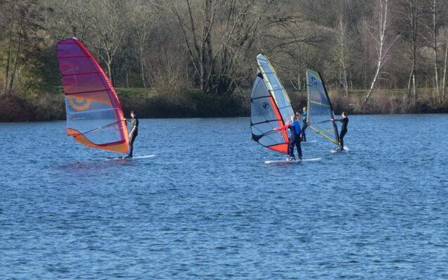 Drei Windsurfer nebeneinander