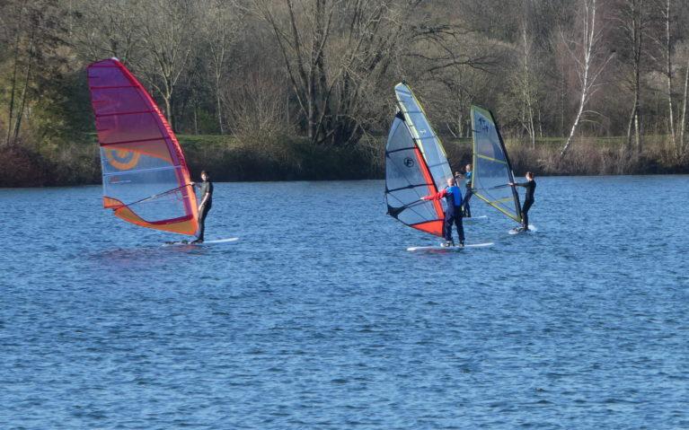 Drei Windsurfer nebeneinander