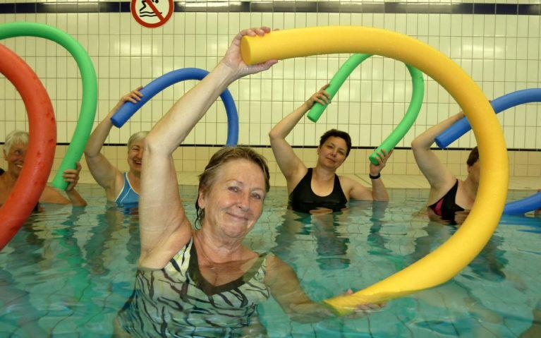 Frauen stehen im Wasser und halten eine Poolnoodle &uuml;ber dem Kopf
