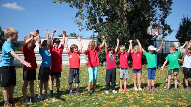 12 Kinder stehen in einer Reihe und halten sich an den H&auml;nden