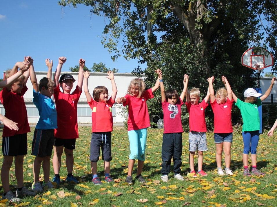 12 Kinder stehen in einer Reihe und halten sich an den H&auml;nden