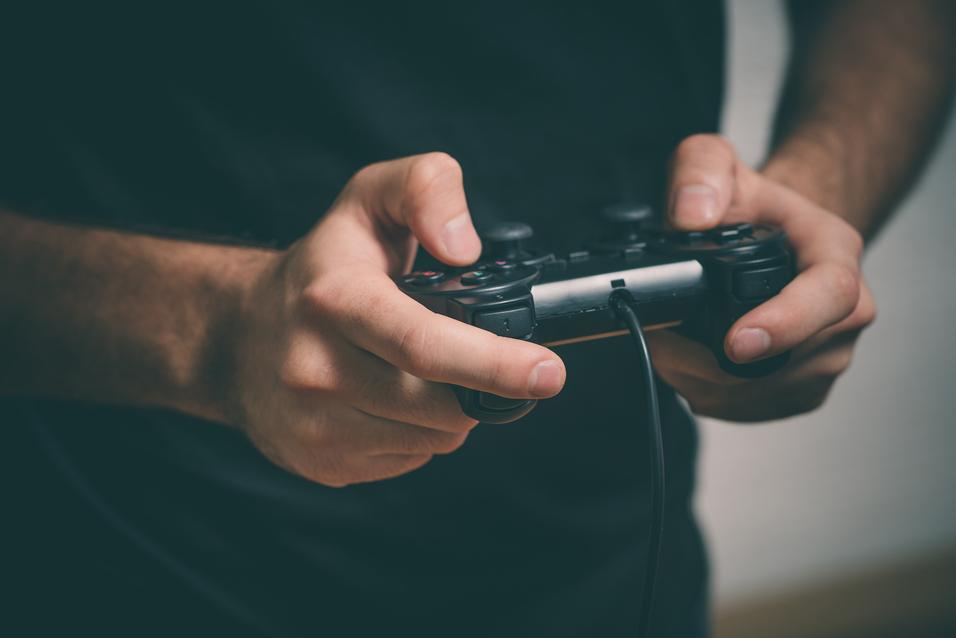 Nahaufnahme von Händen, die einen kabelgebundenen PlayStation-Controller halten. Hintergrund unscharf.